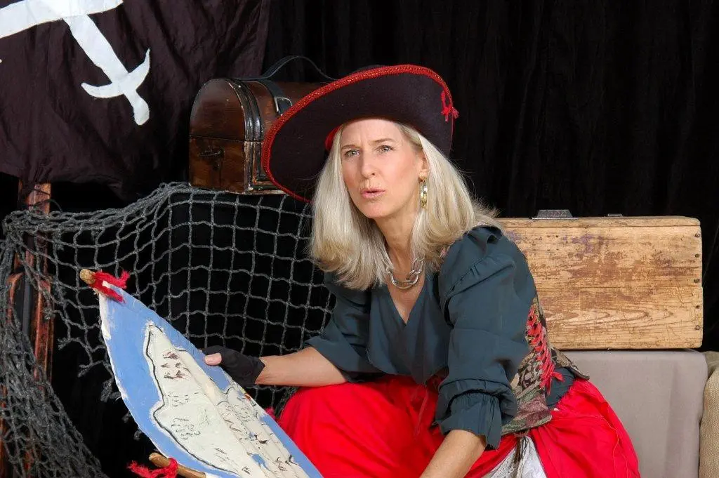 A woman in pirate costume sitting on a bench.