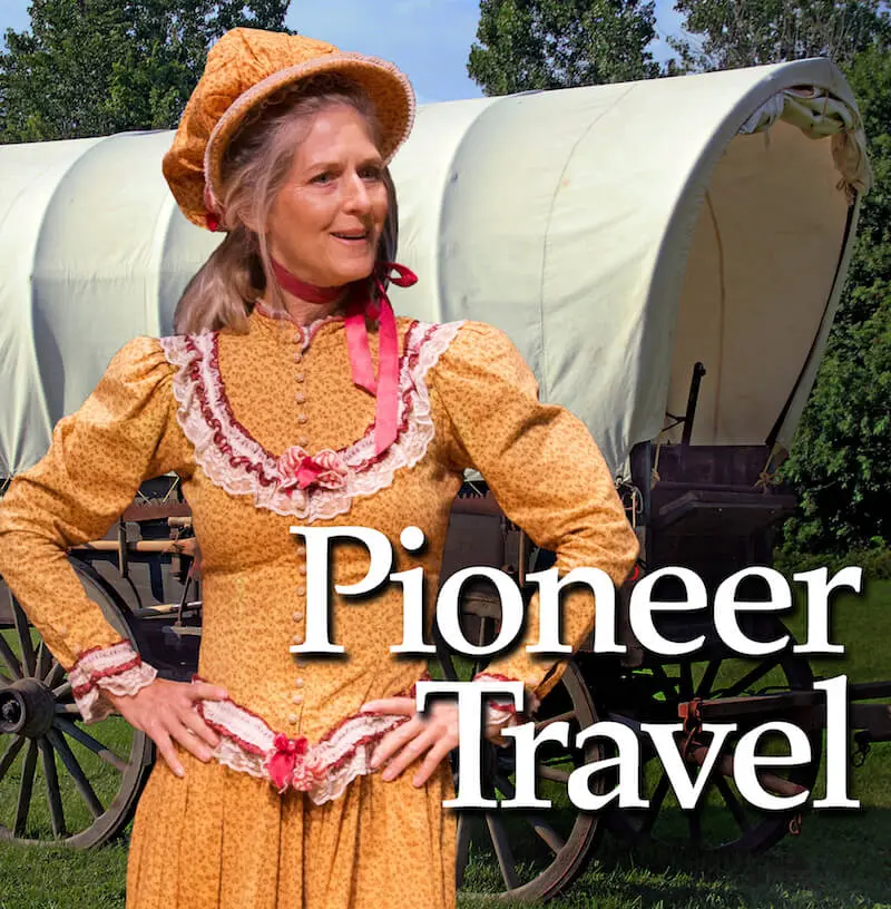 A woman in yellow dress and hat standing next to covered wagon.