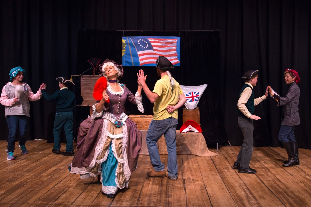 A group of people dancing on stage in front of an american flag.