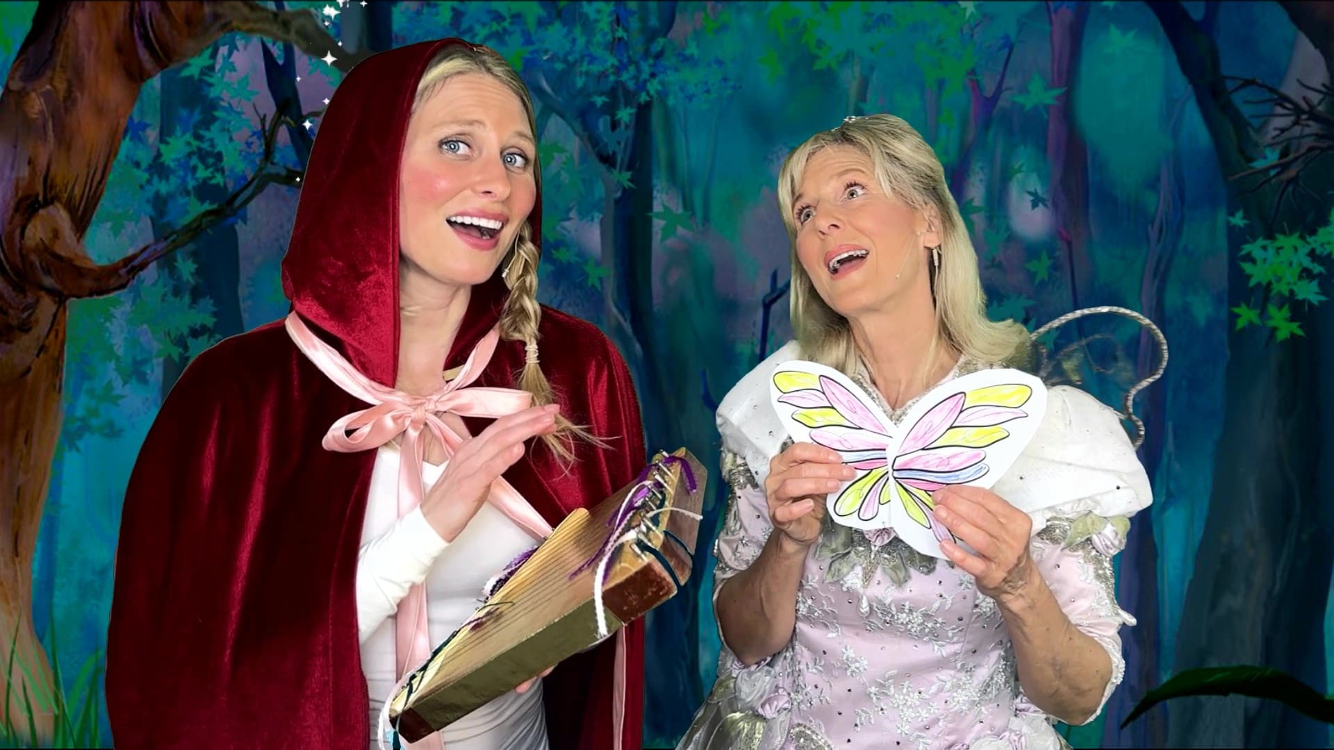 Two women in costumes are holding a butterfly.