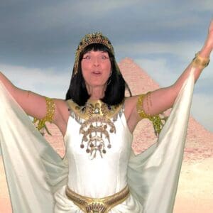 Woman dressed as an ancient Egyptian queen with arms raised.